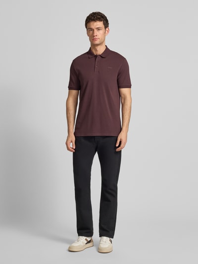 Männermodel trägt Regular Fit Poloshirt aus reiner Baumwolle Modell 'DONOS222' von HUGO, Optik: Unifarben, Label-Print, Piqué, Ganzkörperansicht von vorne.