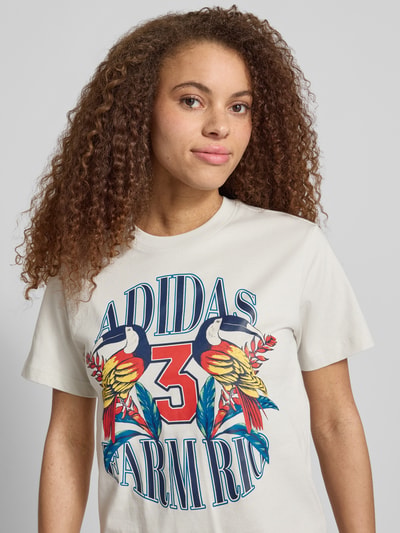 Vrouwenmodel draagt T-shirt met labelprint van adidas Sportswear, puur katoen, regular fit, ronde hals, ruglengte maat S 61 cm, Nahaufnahme Oberkörper.