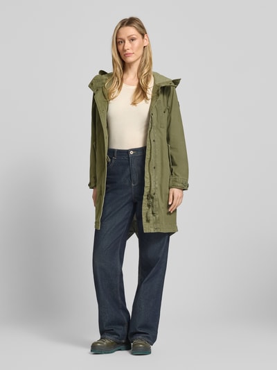 Kobiece modelka nosi Parka mit Kapuze und Pattentaschen Modell 'FREYA' von khujo z bawełny, krój relaxed fit, kaptur z tunel, kieszenie z patką, długość tyłu w rozmiarze S: 94 cm, szerokość ramion w rozmiarze S: 41 cm, szerokość klatki piersiowej w rozmiarze S: 53 cm, długość rękawów w rozmiarze S: 58 cm, oliwkowy kolor, matowa tekstura; całopostaciowy widok z przodu