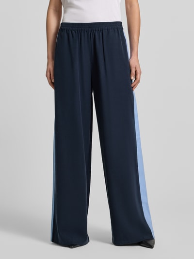 Frauenmodel trägt Fließende Viskose-Hose mit Kontraststreifen - curated by Tinvcb von SIC, Dunkelblau mit hellblauen Seitenstreifen, weites Bein, elastischer Bund, Gesäßtaschen, Ganzkörperansicht von vorne.