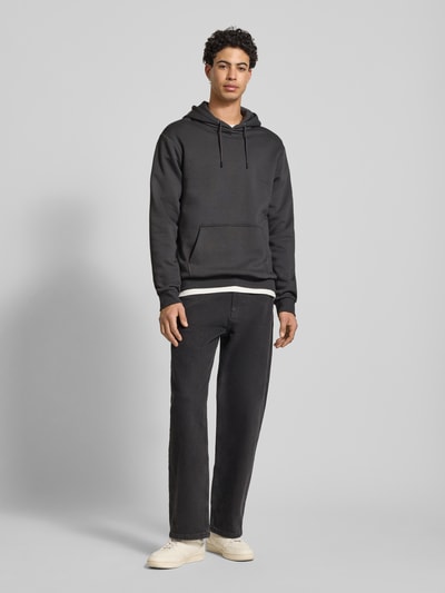 Männermodel trägt Regular Fit Hoodie aus Baumwoll-Mix Modell 'CERES' von Only & Sons, uni schwarz, lange mouw, kangoeroezak, sweatstof, ganzkörperansicht von vorne