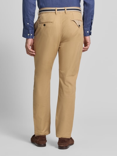 Männermodel trägt beigefarbene Chino mit Gürtel und Eingrifftaschen Modell 'WARREN' von Scotch & Soda, Ganzkörperansicht Rückansicht. Baumwoll-Mix mit Stretch-Anteil, Straight Fit, Doppel-D-Schnalle, seitliche Eingrifftaschen, Gesäßtaschen.