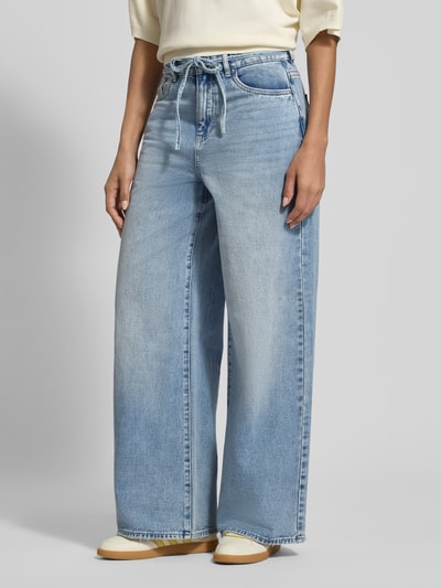 Frauenmodel trägt Loose Fit Jeans aus Baumwoll-Mix Modell 'WIEN' von Vero Moda in Denim-Optik, Bindegürtel, 5-Pocket-Design, Ganzkörperansicht von vorne.