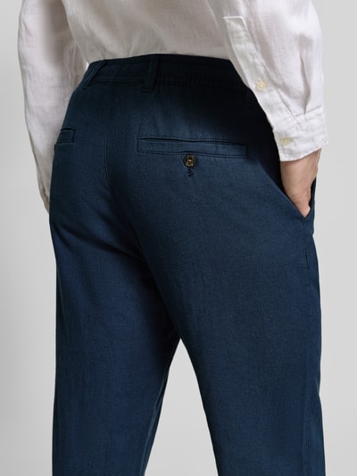 Männermodel trägt Regular Fit Hose aus Baumwoll-Leinen-Mix Modell 'BRODY' von SELECTED HOMME in Dunkelblau, Melange-Optik, Nahaufnahme Rückansicht.