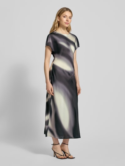 Modelka kobieca nosi Maxikleid mit Rundhalsausschnitt Modell 'QUIMMA' od Someday, szaro-kremowy wzór, prosty krój, widok całej sylwetki z przodu.