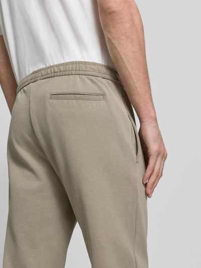 Männermodel trägt Sweatpants mit elastischem Bund von MCNEAL in Beige, Material-Mix mit Baumwoll-Anteil, Gesäßtasche, Nahaufnahme Rückansicht.