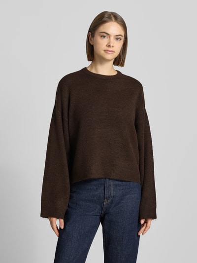 Frauenmodel trägt Relaxed Fit Pullover mit Rundhalsausschnitt Modell 'SIMONI' von ONLY in Dunkelbraun zu Jeans, Damen Pullover von ONLY, Ganzkörperansicht von vorne.
