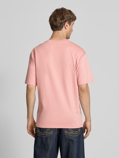 Männermodel trägt Regular Fit T-Shirt mit Logo-Stitching von KARL KANI in Rosa, Reine Baumwolle, Rundhalsausschnitt, Rückenlänge 73 cm, Ganzkörperansicht Rückansicht.