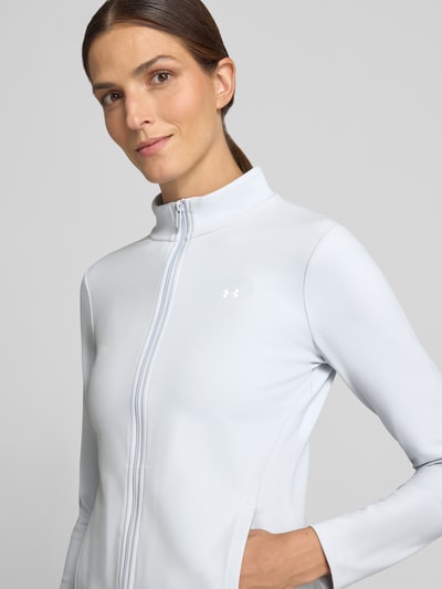 Frauenmodel trägt Slim Fit Trainingsjacke mit Logo-Print von Under Armour, hellgrau, glatte Textur, Nahaufnahme Oberkörper, Damen Trainingsjacke von Under Armour.