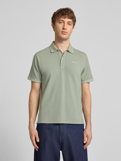 Männermodel trägt Regular Fit Poloshirt aus reiner Baumwolle Modell 'OSCAR' von Pepe Jeans, Optik: Unifarben, Ganzkörperansicht von vorne.