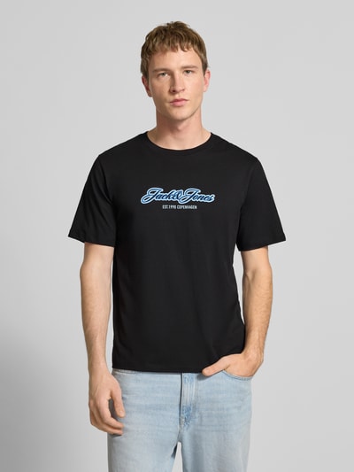 Männermodel trägt Regular Fit T-Shirt mit Logo-Print von JACK & JONES aus reiner Baumwolle, schwarz, Rundhalsausschnitt, Ganzkörperansicht von vorne.