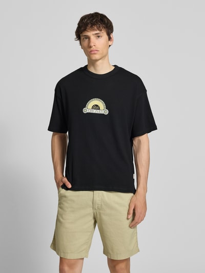 Männermodel trägt T-Shirt mit Label-Print und Rundhalsausschnitt von Jack & Jones, Reine Baumwolle, Regular-Fit, schwarze Farbe, Ganzkörperansicht von vorne.