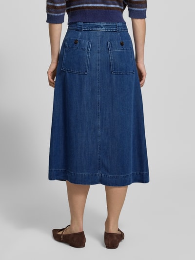 Frauenmodel trägt Jeansrock mit Bindegürtel Modell 'Koda' von MOS MOSH aus reinem Lyocell, A-Linie, Midirock, Gehschlitz, Rückansicht.