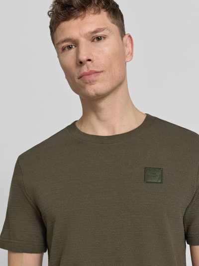Männermodel trägt T-Shirt mit Rundhalsausschnitt von PME Legend in Oliv, Reine Baumwolle, Regular-Fit, Label-Patch, Nahaufnahme Oberkörper. Rückenlänge bei Größe M: 69 cm.