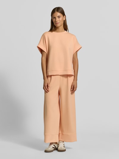Frauenmodel trägt T-Shirt mit elastischen Abschlüssen von Rich & Royal in Pfirsichfarbe, Modal-Mix mit Stretch, Relaxed Fit, Ganzkörperansicht von vorne.