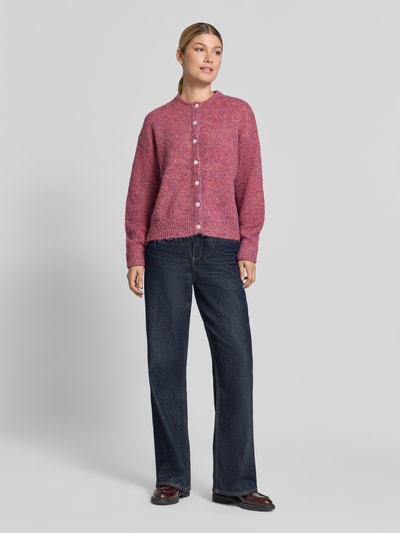 Frauenmodel trägt Relaxed Fit Strickjacke mit Woll-Anteil Modell 'Belablue' von ICHI in Pink, Knopfleiste, Jeans, Ganzkörperansicht von vorne. Elastischer Material-Mix, Rundhalsausschnitt, gerippte Bündchen, langärmlig, Damen Strickjacke.