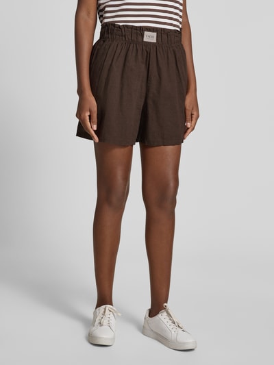 Frauenmodel trägt Regular Fit Stoffshorts aus Leinen-Baumwoll-Mix Modell 'MILLIE' von VILLA SOPHIE mit Allover-Muster und Label Patch, Nahaufnahme Oberschenkelansicht.