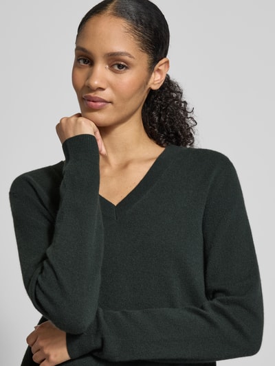 Frauenmodel trägt Strickpullover mit V-Ausschnitt von Christian Berg Woman aus reiner Kaschgora, dunkles Grün, Nahaufnahme Oberkörper.