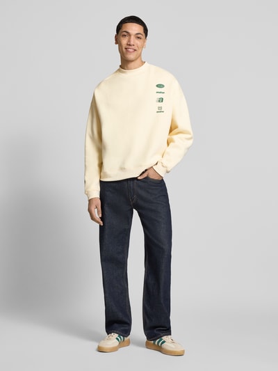 Männermodel trägt Regular Fit Sweatshirt mit Logo-Print von ANOTHER COTTON LAB in Beige, Baumwoll-Mix, Rundhalsausschnitt, elastische Abschlüsse, Ganzkörperansicht von vorne.