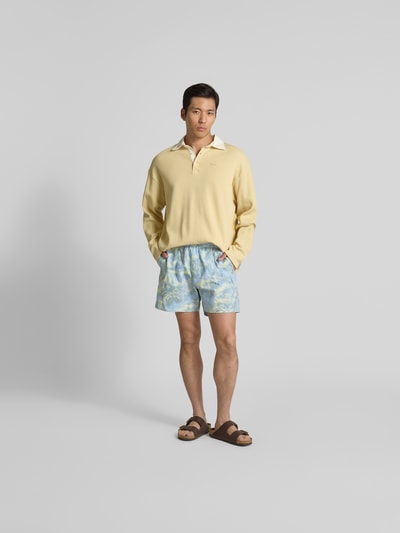 Männermodel trägt Badehose mit Strukturmuster von MAISON KITSUNÉ in Blau mit Taschen, Elastikbund, Gerade Passform, Ganzkörperansicht von vorne.