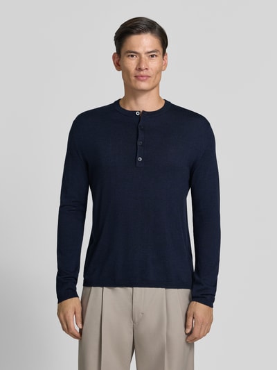 Männermodel trägt Strickpullover mit Henley-Kragen von DRYKORN, reine Baumwolle in Dunkelblau, gerade Form, Ganzkörperansicht von vorne.