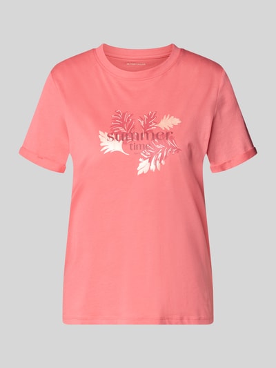 Frauenmodel trägt Regular Fit T-Shirt aus reiner Baumwolle von Tom Tailor in Optik: Unifarben, Motiv-Print, Label-Print, Rundhals, Ärmelform: Kurzarm, Ärmelabschluss mit fixiertem Umschlag, Materialverarbeitung: Jersey, Farbe Rosa, glatte Textur, Ganzkörperansicht von vorne.
