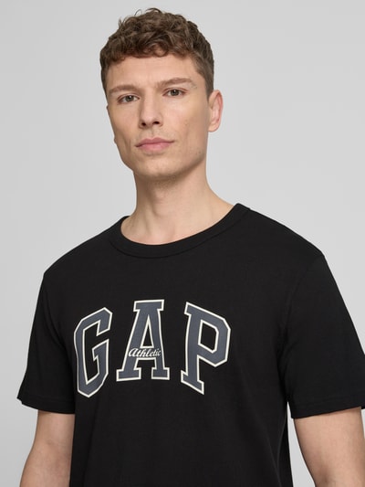 Männermodel trägt T-Shirt mit Logo und Rundhalsausschnitt von GAP in Schwarz, Regular-Fit, Reine Baumwolle, Nahaufnahme Oberkörper.