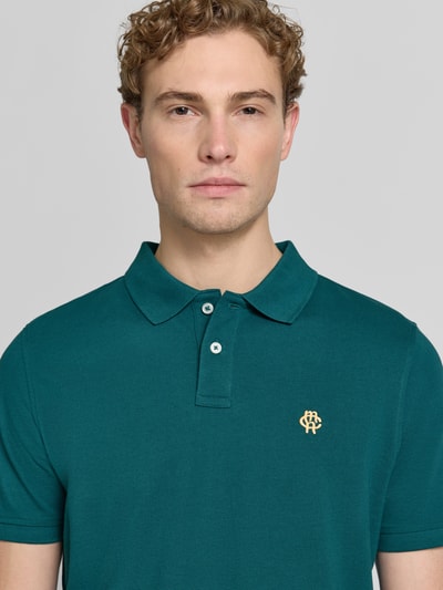 Męski model nosi Slim Fit Poloshirt mit Label-Stitching od MCNEAL z bawełny, krój slim fit, listwa guzikowa, długość tyłu 72 cm, zbliżenie na górną część ciała