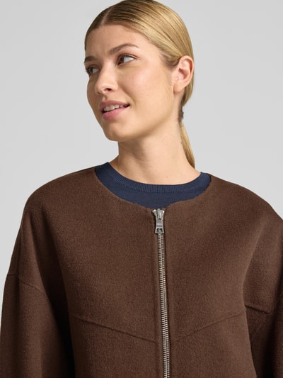 Frauenmodel trägt Doubleface Wolljacke mit abnehmbarer Steppkapuze von Blonde No. 8 in Braun, sichtbarer Zweiwege-Reißverschluss, Nahaufnahme Oberkörper, Relaxed Fit, Wollmischung, elastische Ärmelabschlüsse.