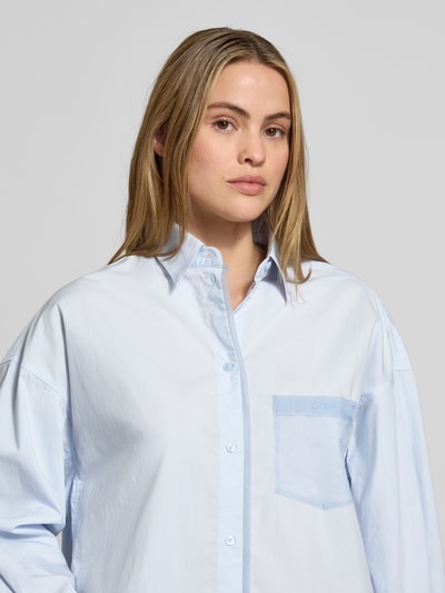 Frauenmodel trägt Oversized Langarmbluse aus reiner Baumwolle Modell 'C_Bonsta' von BOSS Orange, Optik: Unifarben, Hemdkragen, Label-Schriftzug, Brusttasche, Rückenpasse, einreihige Knopfleiste, Manschette, abgerundeter Rumpfabschluss, reine Baumwolle, Nahaufnahme Oberkörper.