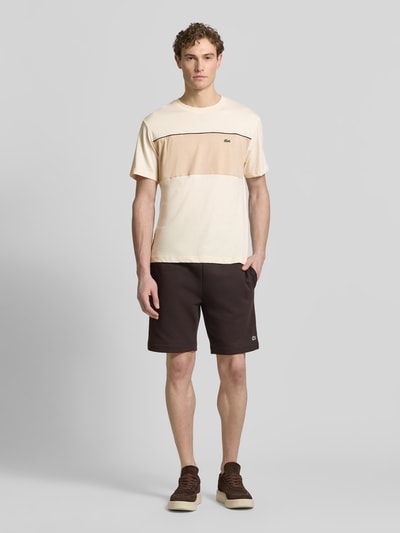 Männermodel trägt Regular Fit T-Shirt aus reiner Baumwolle von Lacoste in Two Tone Optik mit Label Patch, Rundhals, Kurzarm, Jersey, Ganzkörperansicht von vorne.