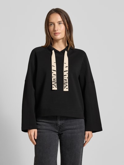 Frauenmodel trägt Oversized Sweatshirt mit Tunnelzug von Marc Cain, schwarzer Baumwoll-Mix mit Stretch-Anteil, Stehkragen; Ganzkörperansicht von vorne.