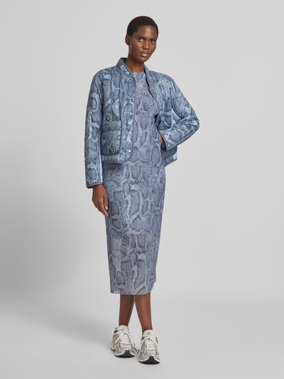 Frauenmodel trägt eng anliegendes Midikleid mit Schlangenmuster von Marc Cain in Blau mit Raglanärmeln und Rundhalsausschnitt, Ganzkörperansicht von vorne