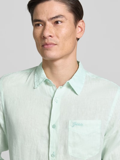 Männermodel trägt Regular Fit Leinenhemd mit Kentkragen und Brusttasche von Guess in zartem Mintgrün, reine Leinenstruktur, Nahaufnahme Oberkörper.