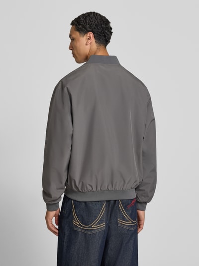 Männermodel trägt graue Bomberjacke mit Stehkragen Modell 'CHARGE' von Jack & Jones, Regular-Fit, Rückansicht, Ganzkörperansicht.
