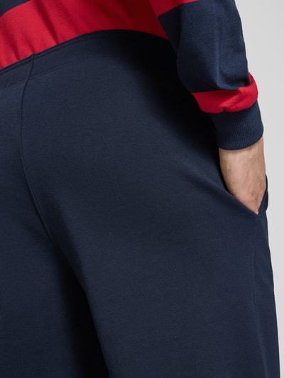 Männermodel trägt Shorts mit elastischem Bund und Label-Stitching von CHAMPION aus Baumwoll-Mix, dunkelblau, Nahaufnahme Hüfte, Regular Fit