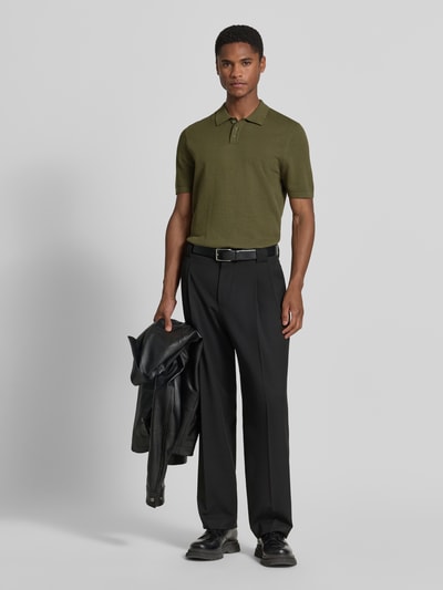 Męski model nosi Slim Fit Poloshirt mit kurzer Knopfleiste Modell 'TRITON' von Drykorn z bawełny, krój slim fit, koszulka polo, długość tyłu w rozmiarze M: 69 cm, kolor oliwkowy, gładka faktura, całkowity widok z przodu.