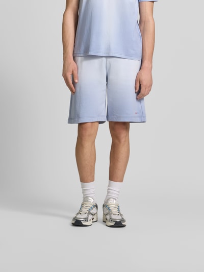 Männermodel trägt Sweatshorts aus reiner Baumwolle von Diesel in Hellblau mit elastischem Bund, Gesäßtaschen, Label-Print, Gerade Passform, Ganzkörperansicht von vorne.