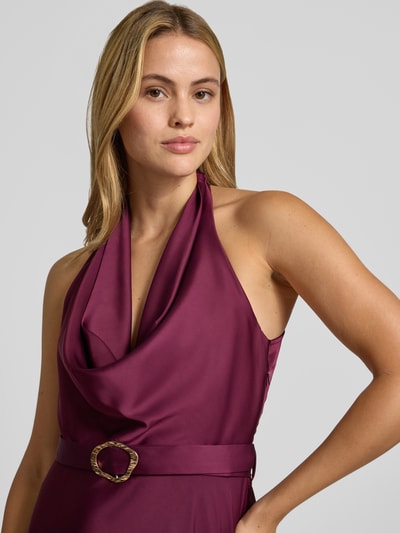 Frauenmodel trägt Abendkleid mit Neckholder von Rinascimento, glänzender Stoff in Weinrot, Stoffgürtel mit Schnalle, Nahaufnahme Oberkörper. Damen Abendkleid von Rinascimento, Material-Mix mit Stretch-Anteil, taillierte Passform.