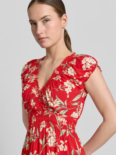 Vrouwenmodel draagt Maxikleid uit viscose met V-hals en smokdetails van Apricot in rood met bloemmotief, getailleerd model, zuiver viscose; ruglengte maat S 121 cm, borstwijdte maat S 38 cm, detailopname bovenlichaam.