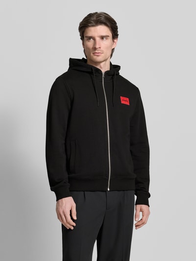 Männermodel trägt zwarte Sweatjack uit puur katoen, los model, capuchon met tunnelkoord, labelpatch, zij-steekzakken, ritssluiting, ruglengte maat XXL 77 cm, mouwlengte maat XXL 74 cm, Sweatjacke aus Baumwolle Modell 'Daple212' van HUGO, Ganzkörperansicht van voren.