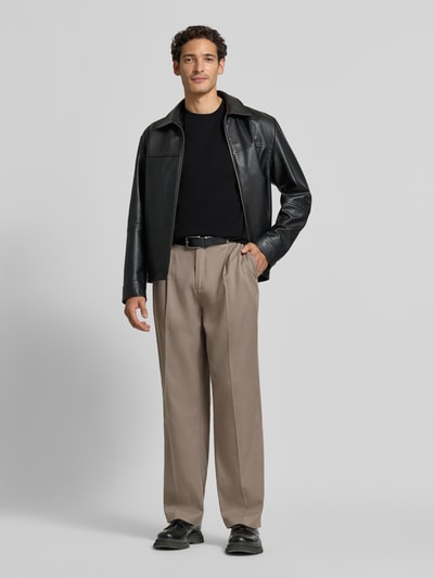 Männermodel trägt Relaxed Fit T-Shirt aus reiner Baumwolle von Antony Morato in Schwarz, kombiniert mit weiter Hose, Ganzkörperansicht von vorne. Damen T-Shirt, Logo-Detail, Rundhalsausschnitt, Rückenlänge bei Größe M: 69 cm.