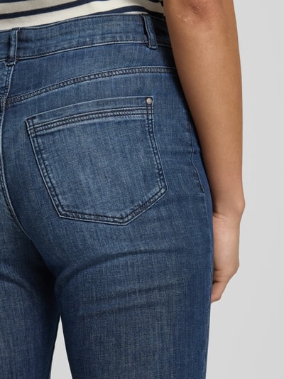 Kobiece modelka nosi Cropped Slim Fit Jeans mit Eingrifftaschen od Christian Berg Woman, bawełniany mix z domieszką stretchu, krój slim fit, cropped, kieszenie boczne, szerokość w rozmiarze 36/28: 38 cm, długość nogawki wewnętrznej w rozmiarze 36/28: 67 cm, tekstura gładka, kolor niebieski, detaliczne ujęcie tylnej części spodni, detailaufnahme.