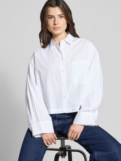 Frauenmodel trägt Oversized Hemdbluse aus reiner Bio-Baumwolle Modell 'Astha' von Selected Femme in Weiß, Ganzkörperansicht von vorne.