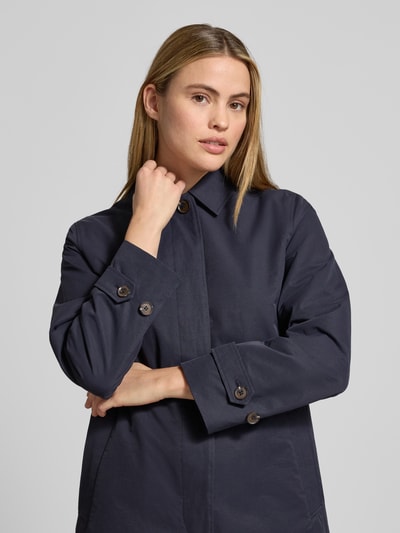 Frauenmodel trägt Mantel mit verdeckter Knopfleiste und Ärmelriegeln von Gant aus dunkelblauem Baumwoll-Mix, Regular-Fit, Nahaufnahme Oberkörper. Rückenlänge 90 cm, Schulterbreite 41 cm, Brustweite 52 cm, Ärmellänge 61 cm, Umlegekragen, Eingrifftaschen.