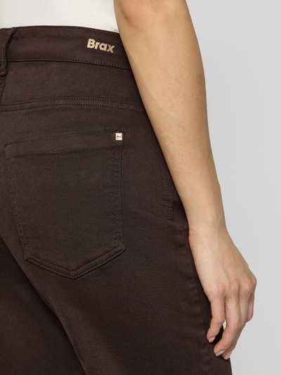 Frauenmodel trägt Wide & Loose Fit Jeans aus Baumwoll-Mix Modell 'Maine' von Brax in Dunkelbraun mit sichtbarer Rücktasche, Nahaufnahme Oberkörper, Damen Wide & Loose Fit Jeans von Brax.