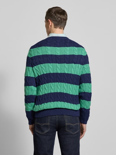 Männermodel trägt Regular Fit Strickpullover aus reiner Baumwolle von Polo Ralph Lauren in Two-Tone Strickoptik mit Zopfmuster, Ganzkörperansicht Rückansicht.
