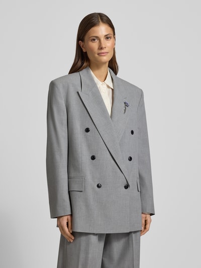 Vrouwenmodel draagt Regular Fit Longblazer met Brosche Modell 'ANTEGI' van HUGO in melange grijs, met reverskraag, lange mouwen en klepzakken, detailopname bovenlichaam.