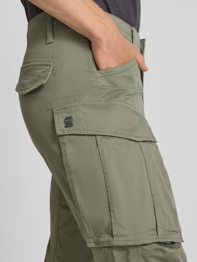 Männermodel trägt olivgrüne Cargo Fit Cargohose aus Baumwoll-Mix von G-Star RAW, sichtbare Taschen, Nahaufnahme Oberschenkel.