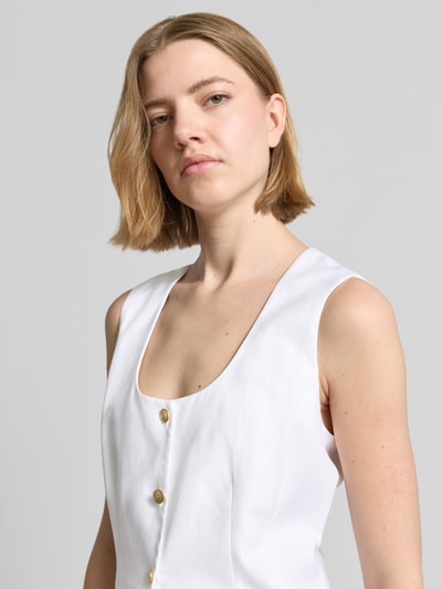 Frauenmodel trägt Slim Fit Weste aus Leinen-Mix von Tommy Hilfiger in Weiß mit goldfarbenen Knöpfen, Nahaufnahme Oberkörper.